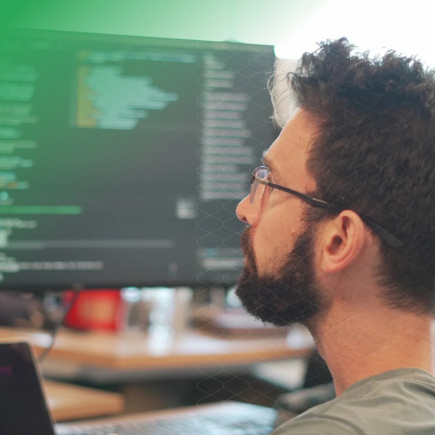 Two people at a desk looking at a monitor together, one pointing at the screen.